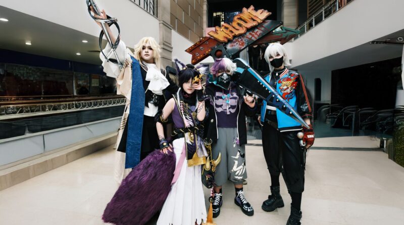 Colorful group of cosplayers posing indoors with detailed costumes and props.